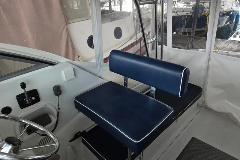 Slide: The Image of 1998 Mainship Pilot 30 helm with blue seating and steering wheel in a covered area. - 20