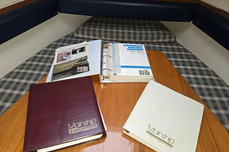Slide: The Image of Manuals and catalogs on a table inside a 1998 Mainship Pilot 30 boat cabin. - 53