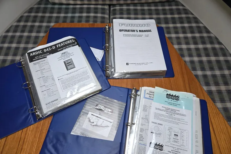 Slide: The Image of Manuals and documents for 1998 Mainship Pilot 30 boat on a wooden table. - 54