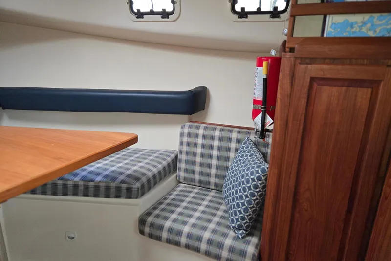 Slide: The Image of 1998 Mainship Pilot 30 cabin interior with plaid seating and wooden cabinetry. - 60