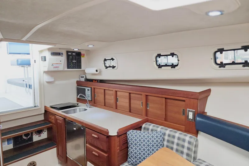 Slide: The Image of 1998 Mainship Pilot 30 interior with kitchenette, wood cabinetry, and seating area. - 63