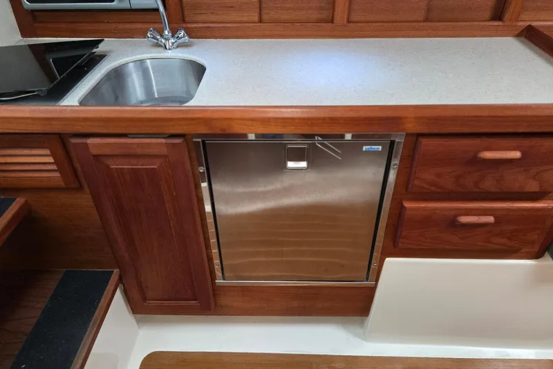 Slide: The Image of 1998 Mainship Pilot 30 galley with stainless steel fridge, sink, and wooden cabinetry. - 65