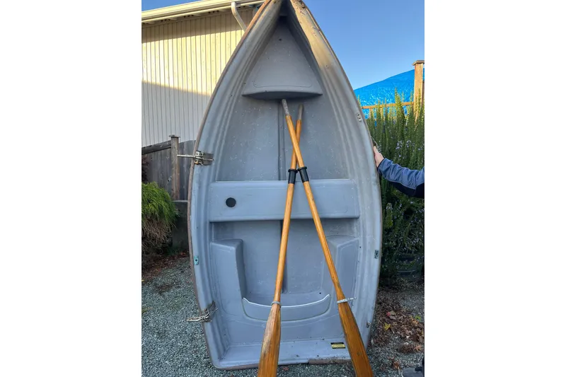 Slide: The Image of 1998 Mainship Pilot 30 boat with wooden oars, displayed vertically outdoors. - 75