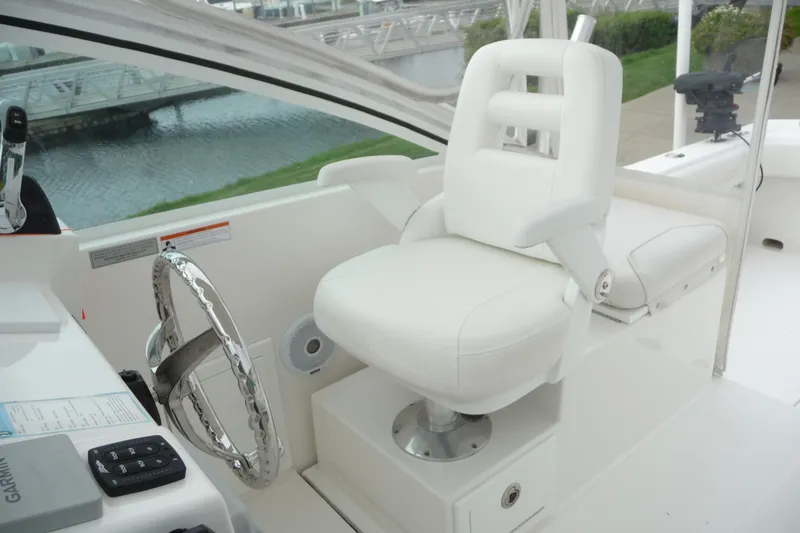 Slide: The Image of 2016 Albemarle 25 Express boat helm with white captain's chair and steering wheel. - 16