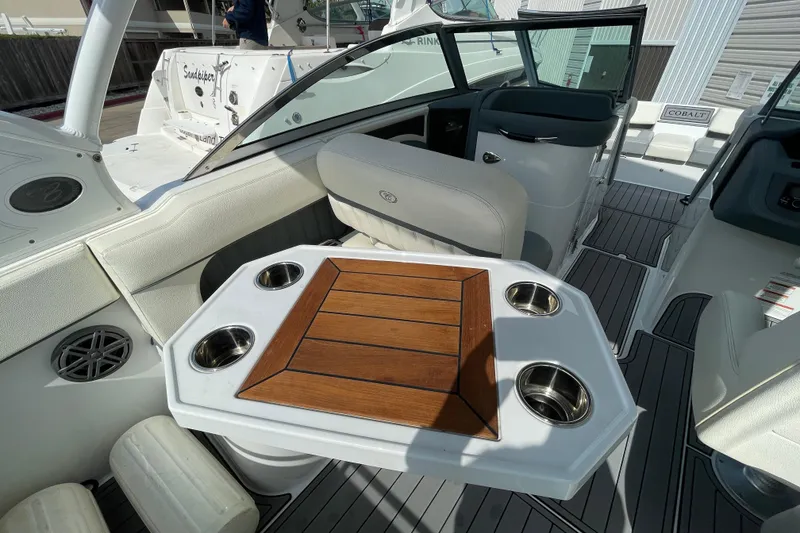 Slide: The Image of 2018 Cobalt 25SC boat interior with wooden table and cup holders. - 10
