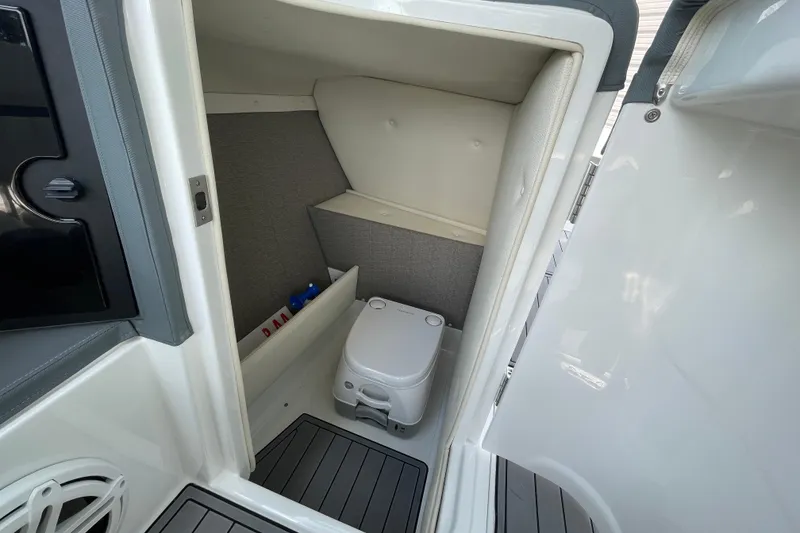 Slide: The Image of 2018 Cobalt 25SC boat interior with compact marine toilet and storage. - 13