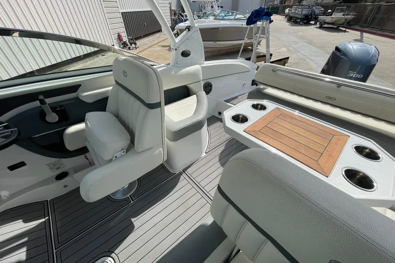 Slide: The Image of 2018 Cobalt 25SC boat interior with seating and table, docked outdoors. - 19