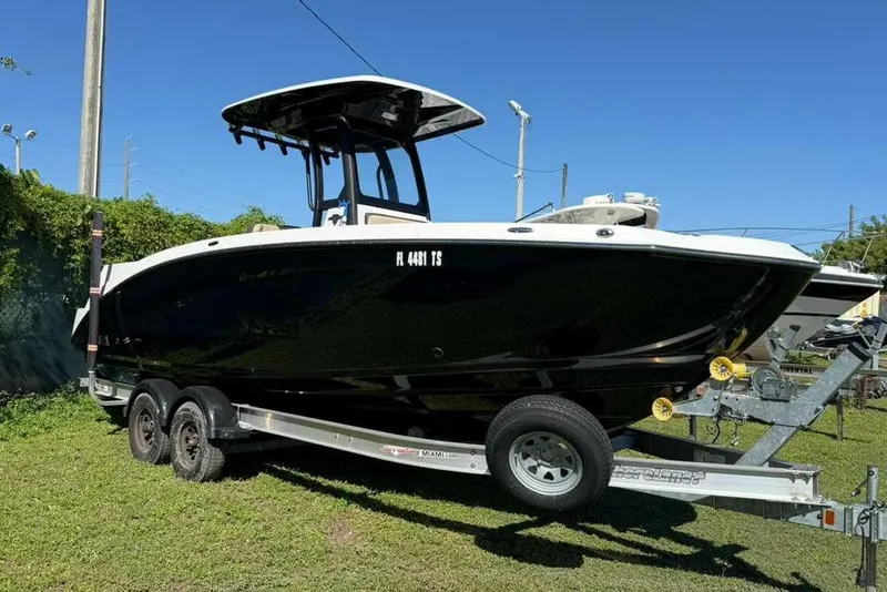 The Image of 2023 Yamaha Boats 255 FSH Sport E on trailer, black hull, sunny day. - 0