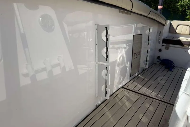 Slide: The Image of 2023 Yamaha Boats 255 FSH Sport E interior with rod holders and cushioned seating. - 10