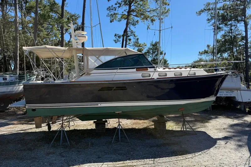 Slide: The Image of 1999 Sabre 36 Express boat on stands, surrounded by trees and other boats. - 1