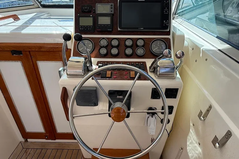 Slide: The Image of 1999 Sabre 36 Express boat helm with steering wheel and navigation controls. - 10