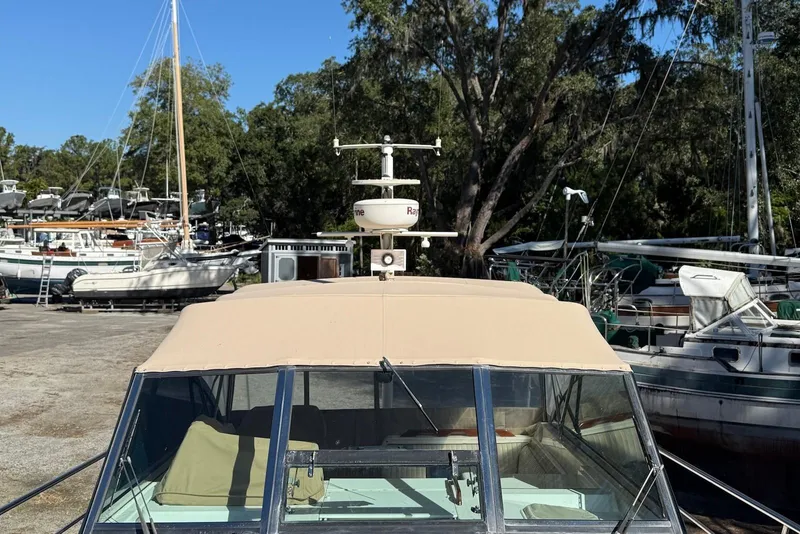 Slide: The Image of 1999 Sabre 36 Express boat docked, surrounded by other vessels and trees. - 16