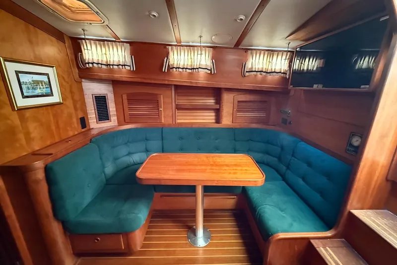 Slide: The Image of 1999 Sabre 36 Express yacht interior with teal seating and wooden table. - 24