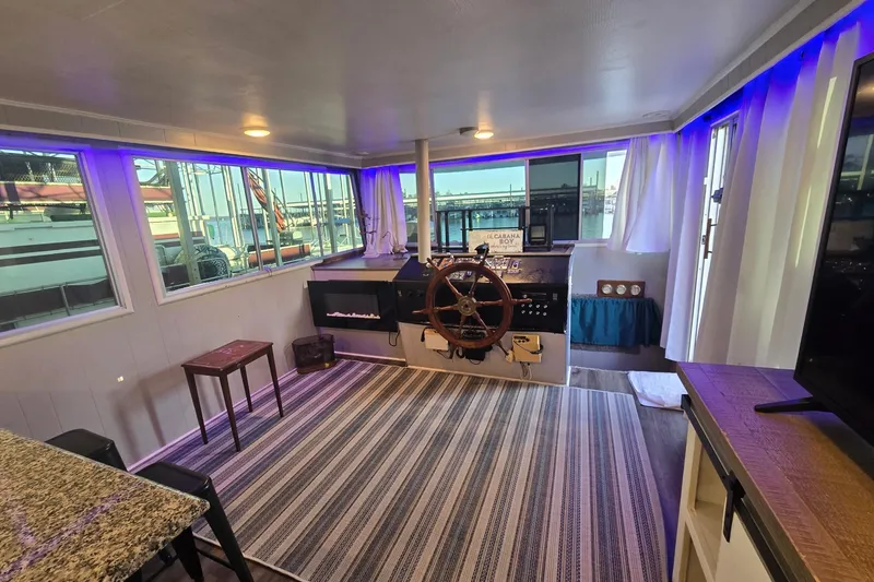 Slide: The Image of Interior of a 1977 Gibson 50 Standard boat with helm, striped rug, and ambient lighting. - 10