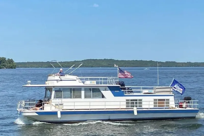 Slide: The Image of 1977 Gibson 50 Standard houseboat cruising on a lake under clear blue skies. - 13