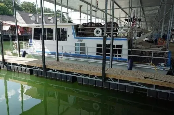Slide: The Image of 1977 Gibson 50 Standard houseboat docked in a marina with green water. - 19
