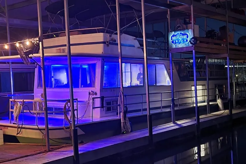 Slide: The Image of 1977 Gibson 50 Standard houseboat with blue interior lighting docked at night. - 2