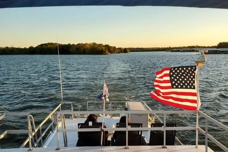 Slide: The Image of 1977 Gibson 50 Standard boat cruising on a lake at sunset with American flag. - 20