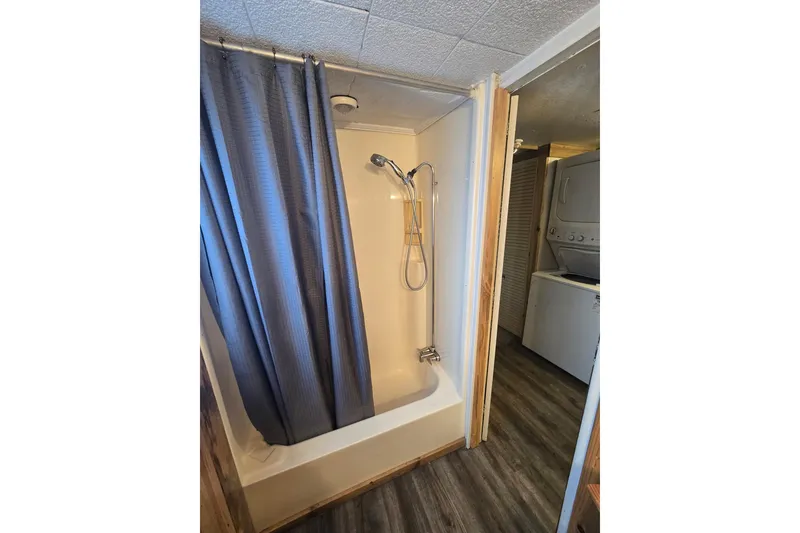Slide: The Image of Small bathroom with shower, blue curtain, and adjacent laundry area. - 9