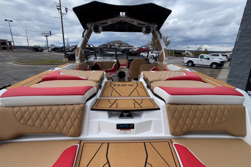 Slide: The Image of 2026 Tigé 24RZX boat interior with tan and red seating, docked under cloudy skies. - 13