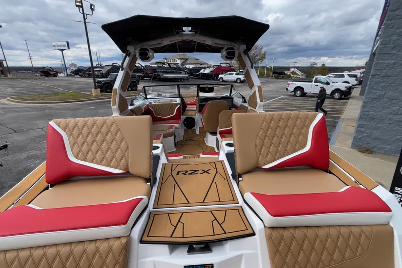 Slide: The Image of 2026 Tigé 24RZX boat interior with tan and red seating, parked outdoors. - 15