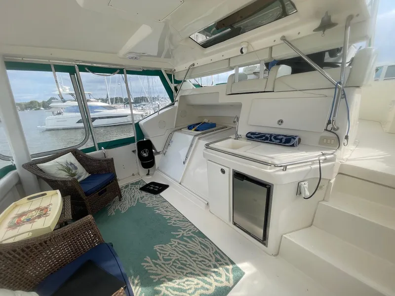 Slide: The Image of 2002 Silverton 392 Motor Yacht interior with seating, mini fridge, and marina view. - 16