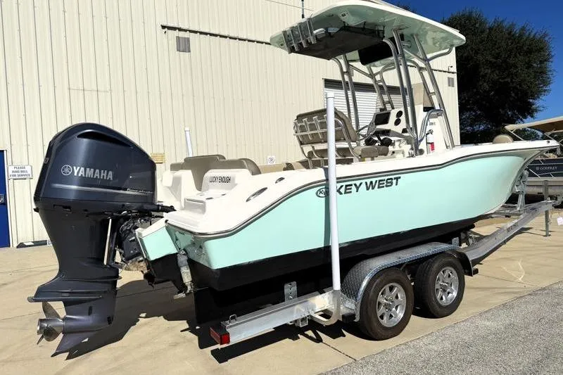 Slide: The Image of 2024 Key West 239 FS boat, white exterior, docked near a warehouse. - 6