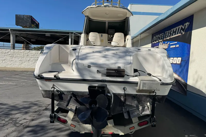 Slide: The Image of 2005 Striper SeaSwirl 2601 boat, rear view, parked outdoors near a fishing store. - 7