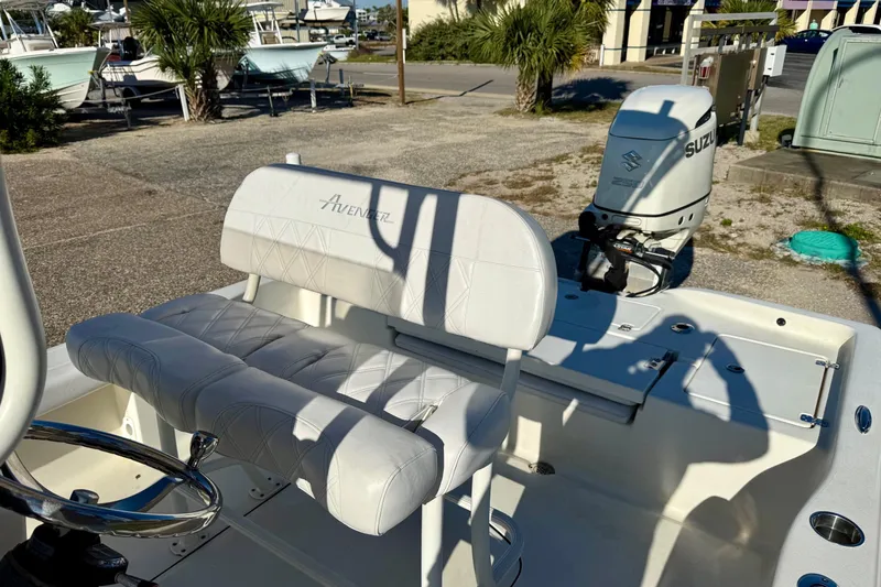 Slide: The Image of 2017 Avenger AV24 boat parked on a marina lot with palm trees and buildings nearby. - 21