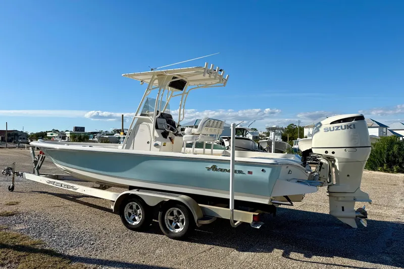 Slide: The Image of 2017 Avenger AV24 boat with outboard motor on a trailer, parked near tall buildings. - 7