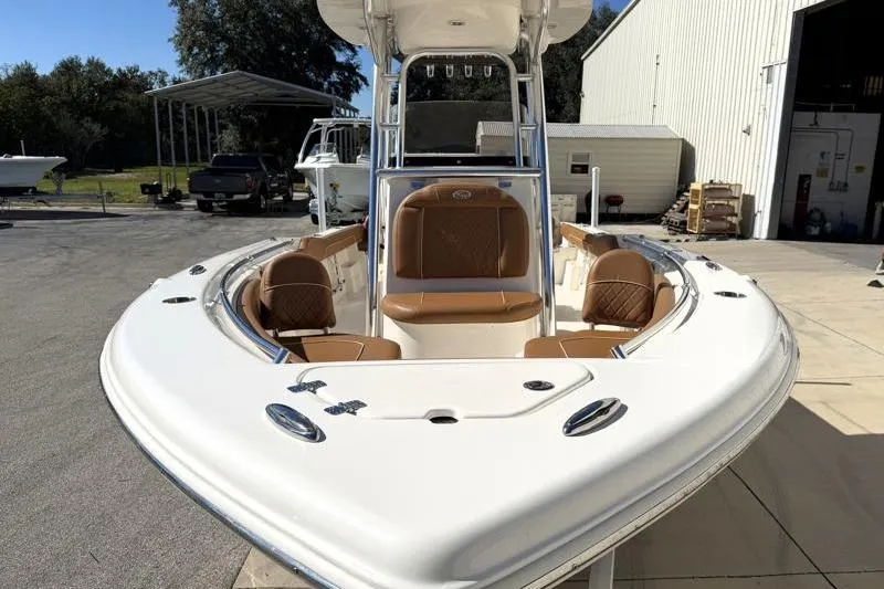 Slide: The Image of 2025 Key West 239 FS boat with tan seating, docked near a warehouse. - 6