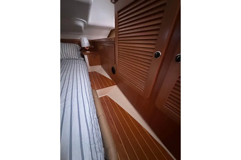 Slide: The Image of Interior of 2003 Catalina 470 yacht with wooden cabinetry and striped bedding. - 11