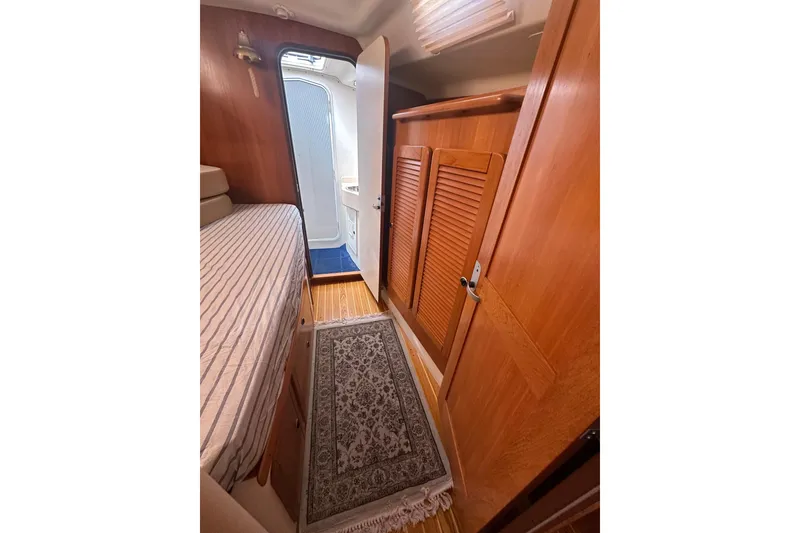 Slide: The Image of Cozy cabin interior of 2003 Catalina 470 yacht with wooden finishes and striped bedding. - 22