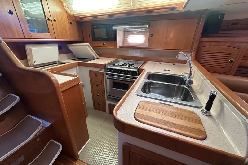 Slide: The Image of 2003 Catalina 470 yacht kitchen with wood cabinetry, dual sinks, and stove. - 8