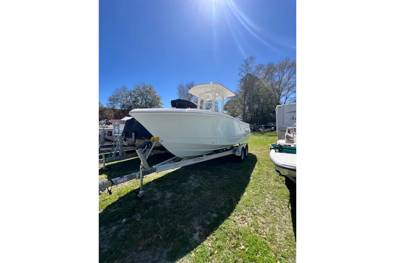 The Image of 2023 Robalo R230 Center Console boat on trailer under clear blue sky. - 1