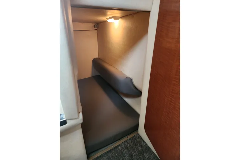 Slide: The Image of 2003 Sea Ray Sundancer 260 cabin interior with cozy sleeping area and soft lighting. - 13