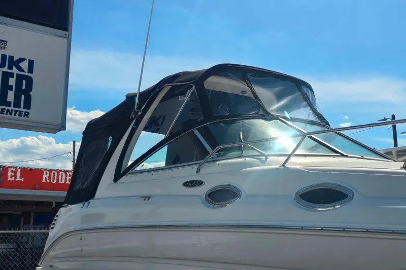 Slide: The Image of 2003 Sea Ray Sundancer 260 boat with black canopy under clear blue sky. - 17