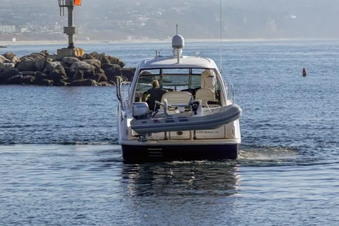 Slide: The Image of 2005 Sea Ray 390 Sundancer yacht navigating coastal waters near rocky shoreline. - 3