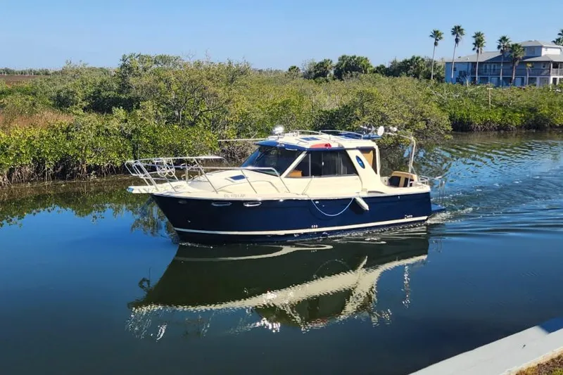The Image of 2012 Cutwater 26 boat cruising on a calm river with lush greenery. - 0