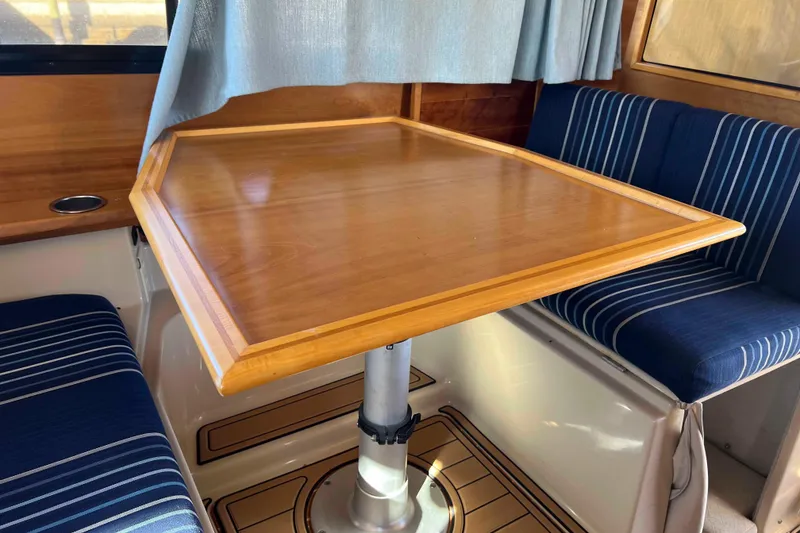 Slide: The Image of Interior of 2012 Cutwater 26 boat with wooden table and striped seating. - 26