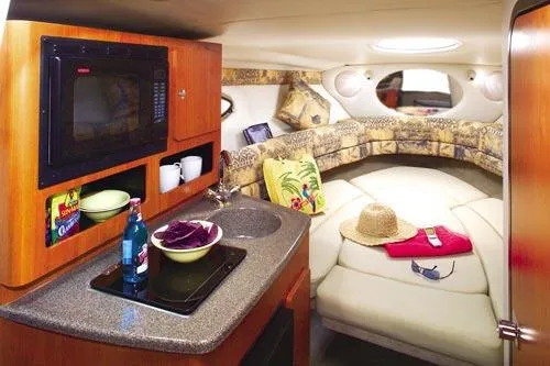 Slide: The Image of 2006 Crownline 250 CR boat on stands, blue and white hull, sunny day. - 2