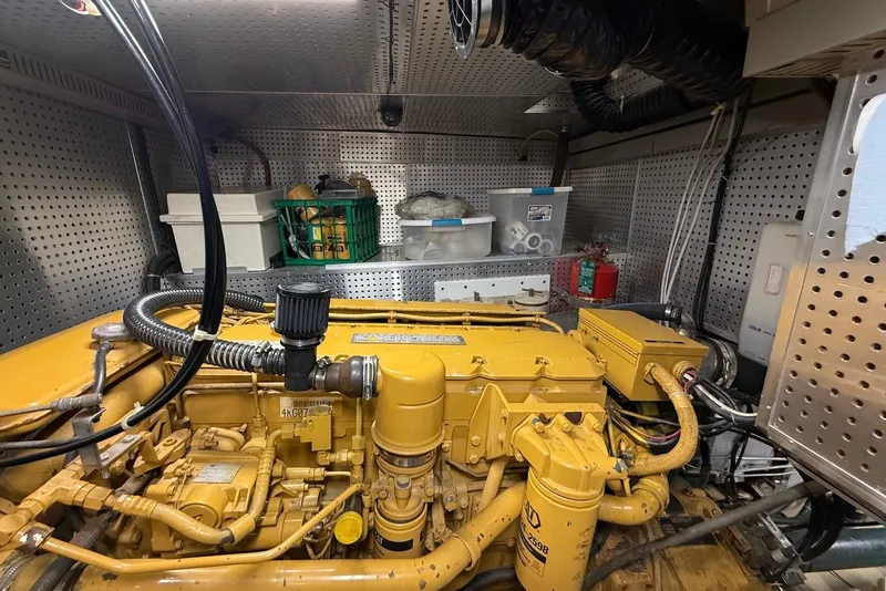 Slide: The Image of Engine room of 1998 Krogen Express 49 yacht, featuring a yellow engine and organized storage. - 77