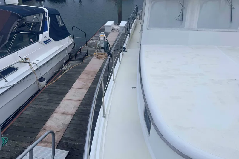 Slide: The Image of 1998 Krogen Express 49 yacht docked at marina, showcasing spacious deck and sleek design. - 14