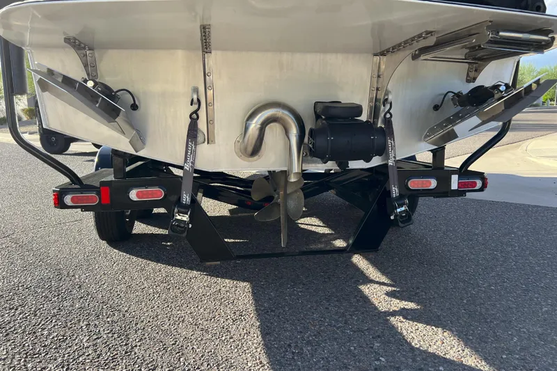 Slide: The Image of Rear view of 2024 Montara 23 SURF BOSS 2.0 boat on trailer, showing propeller and exhaust. - 2