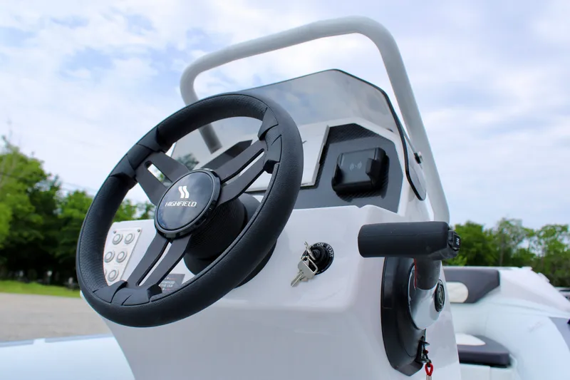 Slide: The Image of 2024 Highfield Sport 460 boat steering console with controls and ignition keys. - 14