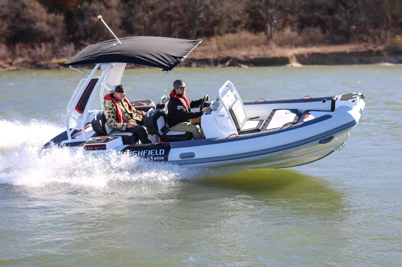 Slide: The Image of 2026 Highfield Velox 560 boat cruising on water with two passengers under a canopy. - 22