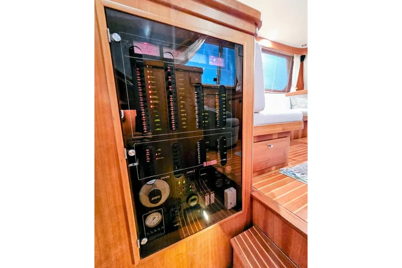 Slide: The Image of Electrical panel inside 2005 Alden 49 Flybridge Express Cruiser, featuring wooden interior and seating area. - 19