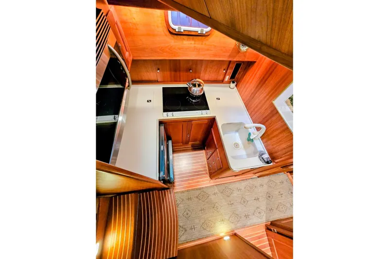 Slide: The Image of Interior of 2005 Alden 49 Flybridge Express Cruiser, featuring a compact, elegant kitchen area. - 26