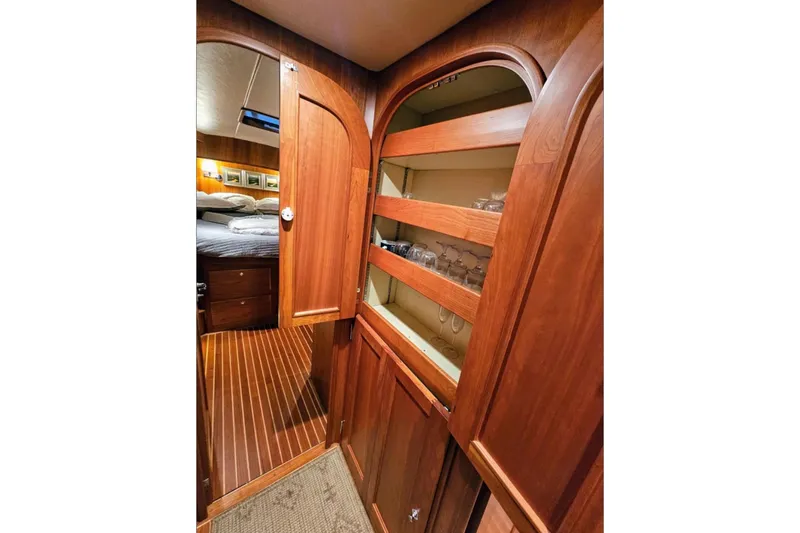 Slide: The Image of Interior of 2005 Alden 49 Flybridge Express Cruiser with wooden cabinetry and glass storage. - 32