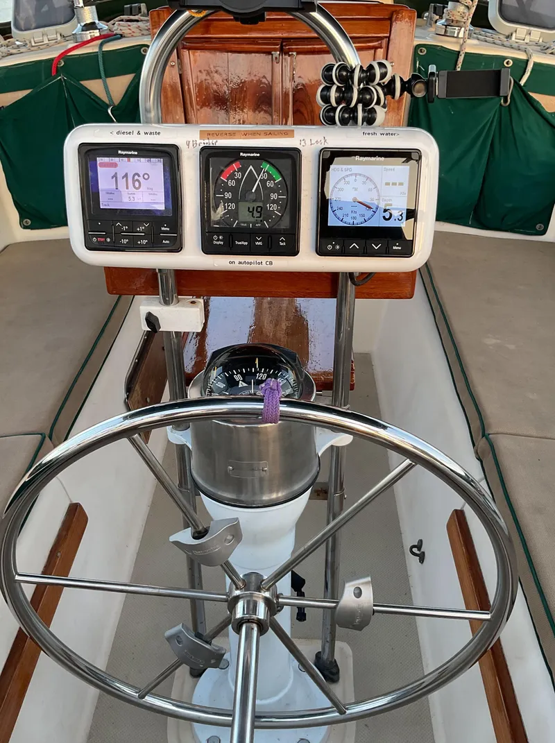 Slide: The Image of 1990 Island Packet 32 sailboat cockpit with navigation instruments and steering wheel. - 21